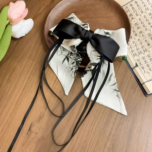 Détail d'une pince à cheveux néo-chinoise avec nœud noir et rubans en soie peints