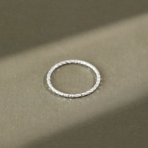 Minimalist S925 sterling silver ring with faceted texture on olive green background