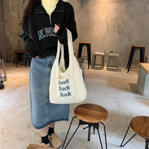 Detail of white plush lamb wool tote bag with blue luck luck luck print on front