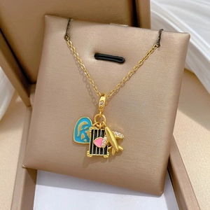 Detailed close-up of titanium gold necklace with airplane, luggage and passport charms
