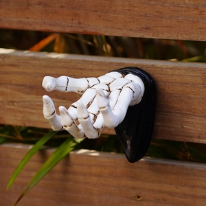 Close-up of white resin skull hand hook mounted on wooden fence for wall decoration