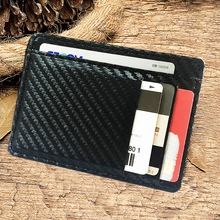 Close-up of black PU leather card holder with carbon fiber texture on rustic wood
