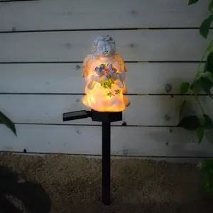 Close-up of solar resin angel statue with warm yellow glow and pink flower details