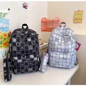Detail of plaid backpacks in black and light blue with matching pencil cases on a desk
