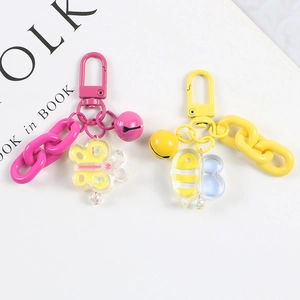 Close-up of colorful cartoon keychains with acrylic bee and butterfly charms on white