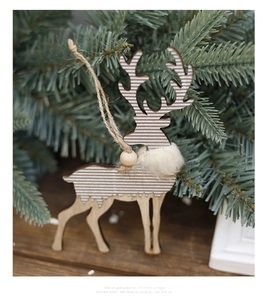 Wooden Christmas reindeer ornament with faux fur and twine hanging on a pine branch