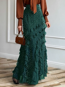 Deep green polka dot maxi skirt with ruffle detail modeled in a minimalist studio setting
