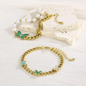 Detail of gold Cuban chains with green enamel butterflies and pearl splicing bracelets