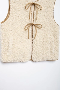 Detail of cream fleece vest with brown trim and front tie closure for women