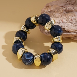 Dettaglio di perle blu marmorizzate e distanziatori dorati geometrici su un bracciale