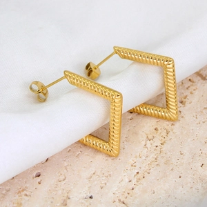 Macro shot of gold square stud earrings with twisted texture on elegant silk background