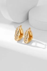 Detailed close-up of golden U-shaped huggie earrings with hollow star and heart cubic zirconia