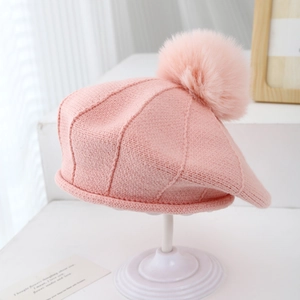Détail du béret en maille rose avec pompon montrant la texture douce et les coutures