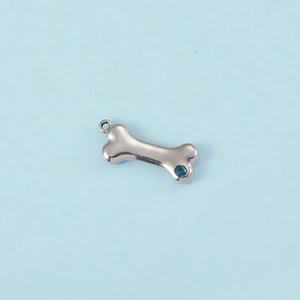 Detailed macro shot of a silver bone-shaped pendant with a sparkling blue zircon stone