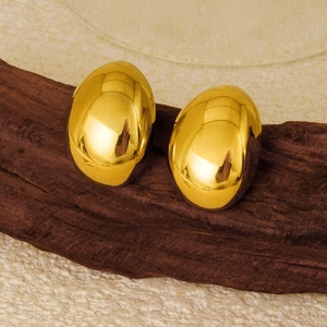 Detailed view of 18K gold oval stud earrings with polished finish on a wooden base