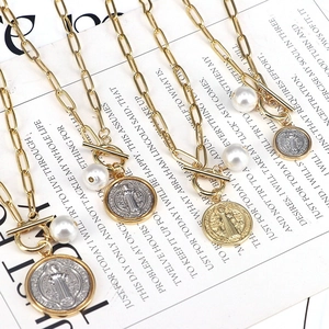 Detail of vintage gold and silver layered necklaces with saint medals and pearl charms