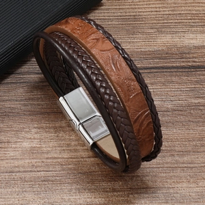 Detail of multi-layer leather braided bracelet with magnetic alloy clasp on wood surface