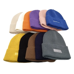 Flat lay of knit beanies in various colors with embroidered The Focus circular patch
