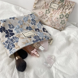 Détail de la texture jacquard floral et de la fermeture éclair du sac à cosmétiques