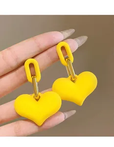Detail shot of bright yellow heart-shaped acrylic earrings held in hand