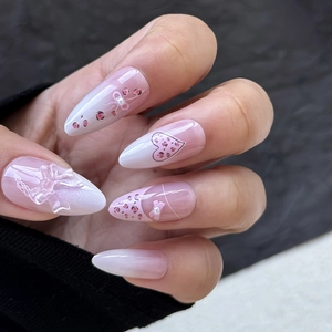 Détail de faux ongles amande avec nœuds 3D, imprimé léopard rose et motifs de cœur