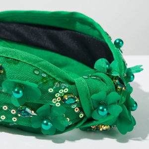 Détail du serre-tête vert émeraude orné de paillettes, perles et fleurs en tissu