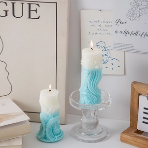 Detail of lit gradient blue pillar candles with textured wave patterns in home setting