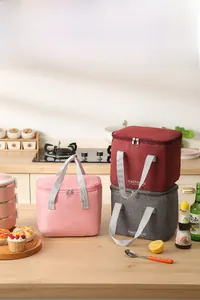 Three colors of insulated lunch bags with dual zippers in a modern kitchen setting