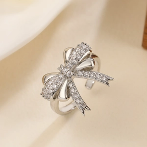 Macro shot of silver bow ring featuring white zircon stones and adjustable open band detail