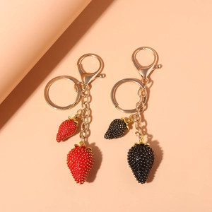 Detail of red and black strawberry keychain pendants with golden metal lobster clasps
