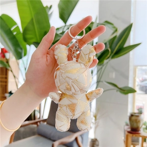 Detailed view of white plush rabbit keychain with gold geometric patterns and metal clasp