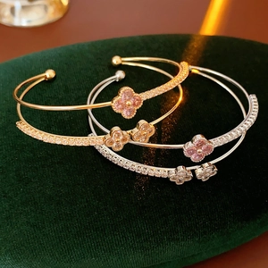 Detail of four-leaf clover zircon double-layer open bracelets on green velvet box