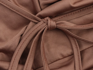 Macro detail of sexy halter top fabric showing fine stitching and knotted cord in chocolate brown