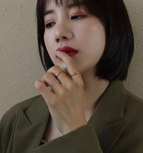 Close-up of dual gold link chain rings worn by a model in a modern fashion style
