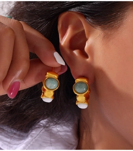 Detail of gold geometric earrings with turquoise stone inlay and hanging white pearls