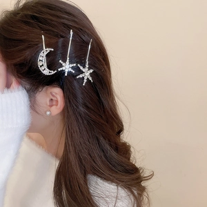 Detail showing moon and star rhinestone hair clips worn on long wavy hair