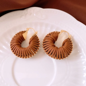 Vue détaillée de créoles rétro en cuir tressé sur une assiette décorative en céramique