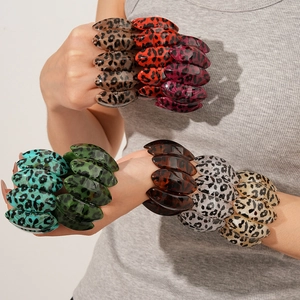 Close-up of stacked leopard print resin bangles in various colors on a model's wrist