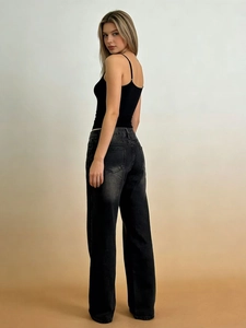 Vista posteriore di eleganti jeans neri a gamba larga da donna con canotta nera