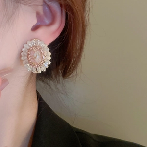 Close-up of vintage palace-style floral earrings with pink crystals on model ear