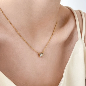 Detail view of a dainty gold chain necklace featuring a square step-cut zircon pendant