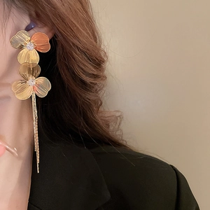 Gros plan de boucles d'oreilles fleur dorée avec longues franges métalliques sur mannequin