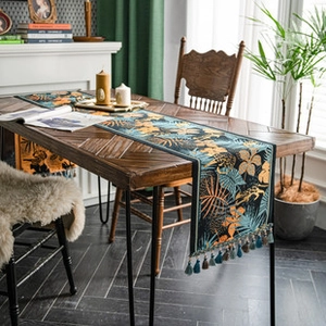 Close-up of vintage floral table runner with blue patterns and fringe tassels