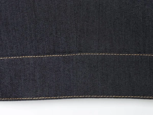 Gros plan sur le tissu denim foncé avec des détails de surpiqûres jaunes contrastées