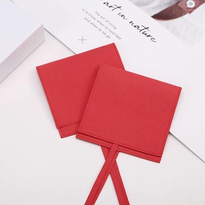 Macro view of textured red jewelry pouches with matching ribbons and a gift card detail