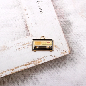 Macro view of a vintage radio enamel pendant in red and gold on a rustic wood frame