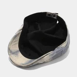 Detail view of washed denim beret featuring marble texture and adjustable metal buckle strap