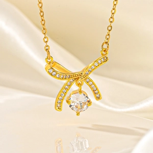 Elegant gold bow pendant necklace with sparkling cubic zirconia on soft silk background