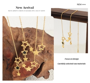 Detail of gold star pendant necklace with hollow and black enamel charms on wood base