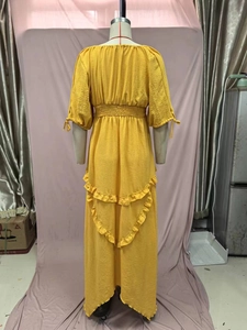 Detail of yellow pleated dress featuring elastic waist and layered ruffle hem